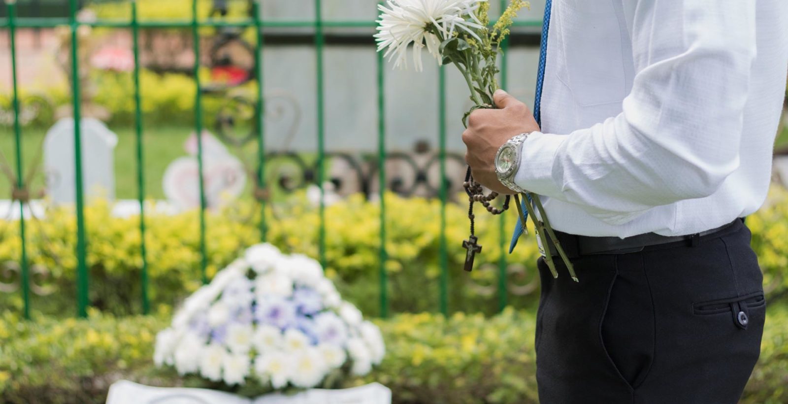 man holding flowers in a cemetery